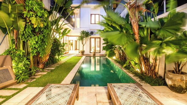 Zona de piscina con vista despejada, rodeada de abundante vegetación y un césped cuidado.