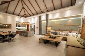A spacious living area with a dining table, sofa, and kitchen in the background.