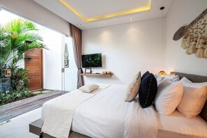 Une chambre à coucher moderne avec un grand lit, une télévision et une petite étagère.