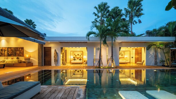 Ein modernes Haus mit Swimmingpool, Holzterrasse und einem gut beleuchteten Innenraum.
