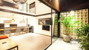A modern kitchen with a dining area, a large potted plant, and a staircase leading to an upper level.