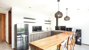 A modern kitchen with a wooden dining table, built-in appliances, and pendant lighting.