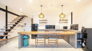 A modern kitchen with a central island, built-in appliances, and a staircase with wooden steps. - Expansive Loft 200m from Canggu Beach Haven<br>Part of Noma Estate (Pererenan)