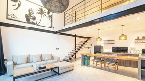 A modern living room with a sofa, coffee table, and a staircase leading to an upper level. - Expansive Loft 200m from Canggu Beach Haven<br>Part of Noma Estate (Pererenan)