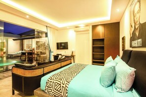 Une chambre d’hôtel moderne dotée d’un grand lit, d’un coin salon avec un canapé et une petite table, d’une grande fenêtre donnant sur une piscine et d’un téléviseur fixé au mur.