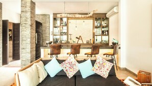 Una sala de estar moderna con un sofá, una zona de bar con estanterías y un espejo grande.
