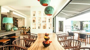 Un comedor moderno con una mesa de madera, sillas de mimbre y un frutero.