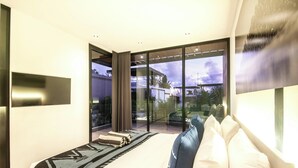 A modern hotel room with a large bed, a view through glass doors, and a large window. - Chic 4BR, 200m to Canggu's Blissful Beach Haven (Pererenan)