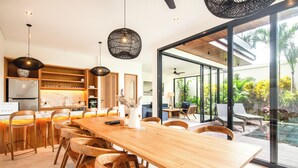 A modern kitchen with wooden cabinets, a large island, and pendant lighting. - Beachside Bliss: New 5BR Villa Canggu (Pererenan)