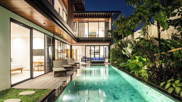 A modern house with a swimming pool, outdoor seating, and lush greenery. - Beachside Bliss: New 5BR Villa Canggu (Pererenan)