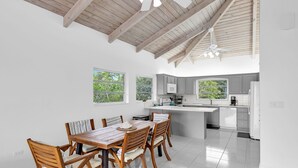 A modern kitchen with a central island, grey cabinets, and a dining area with wooden chairs and a table. - Oceanfront Oasis: Dockside Bliss (Tavernier)