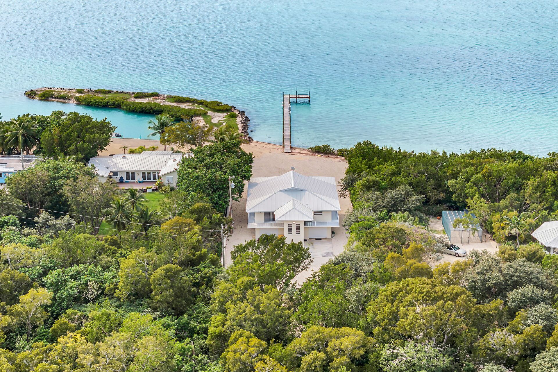 A coastal property with a large house, a dock, and lush greenery.