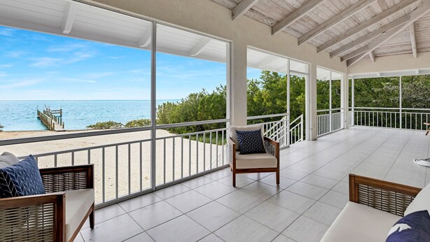 A covered outdoor area with a view of the sea, featuring a chair and a table. - Oceanfront Oasis: Dockside Bliss (Tavernier)