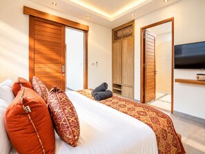 Hotellihuone, jossa on sänky, vaatekaappi, televisio ja kylpyhuone.