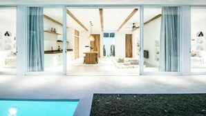 A modern house with a spacious interior, large sliding glass doors, a dining area, and a pool. - New 2br villa 4mins to Bingin beach (Uluwatu)