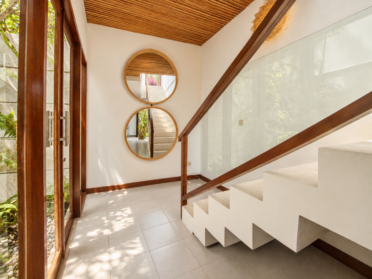 A modern staircase with a glass railing and wooden accents, leading to a white interior space.