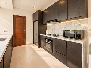 A modern kitchen with dark cabinetry, a built-in microwave, and a stainless steel oven. - Exquisite 2BR Villas, Brawah, 300m to Beach (Kuta Utara)