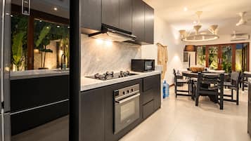 A modern kitchen with dark cabinetry, a gas stove, a microwave, and a dining area with a table and chairs.