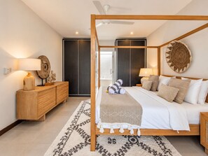 A modern bedroom with a four-poster bed, a wooden dresser, a round wall decoration, and a patterned rug. - Exquisite 2BR Villas, Brawah, 300m to Beach (Kuta Utara)
