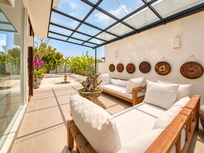 A sunlit patio with a wooden sofa, a bench, and a potted tree. - Exquisite 2BR Villas, Brawah, 300m to Beach (Kuta Utara)
