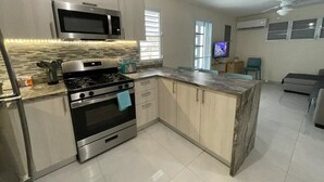 A modern kitchen with a built-in microwave, stove, and oven. There is a dining area with a TV and seating. - Spacious Home with Beach Gear and Outdoor Space (Vieques)