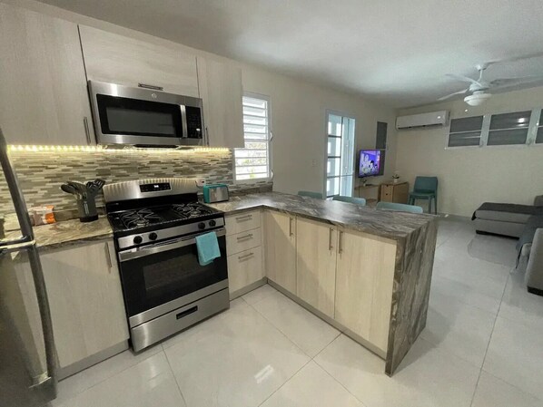 A modern kitchen with a built-in microwave, stove, and oven. There is a dining area with a TV and seating.