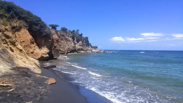 A coastal landscape with a rocky cliff and a beach. - Spacious Home with Beach Gear and Outdoor Space (Vieques)