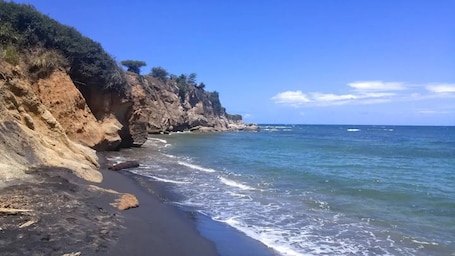 A coastal landscape with a rocky cliff and a beach.