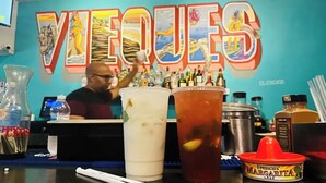 A bar area with a large sign reading "VIEQUES," a bartender, and various beverages and condiments on the counter. - Spacious Home with Beach Gear and Outdoor Space (Vieques)