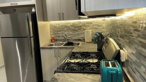 A kitchen with a stainless steel refrigerator, a gas stove, a sink, and a teal toaster. - Spacious Home with Beach Gear and Outdoor Space (Vieques)