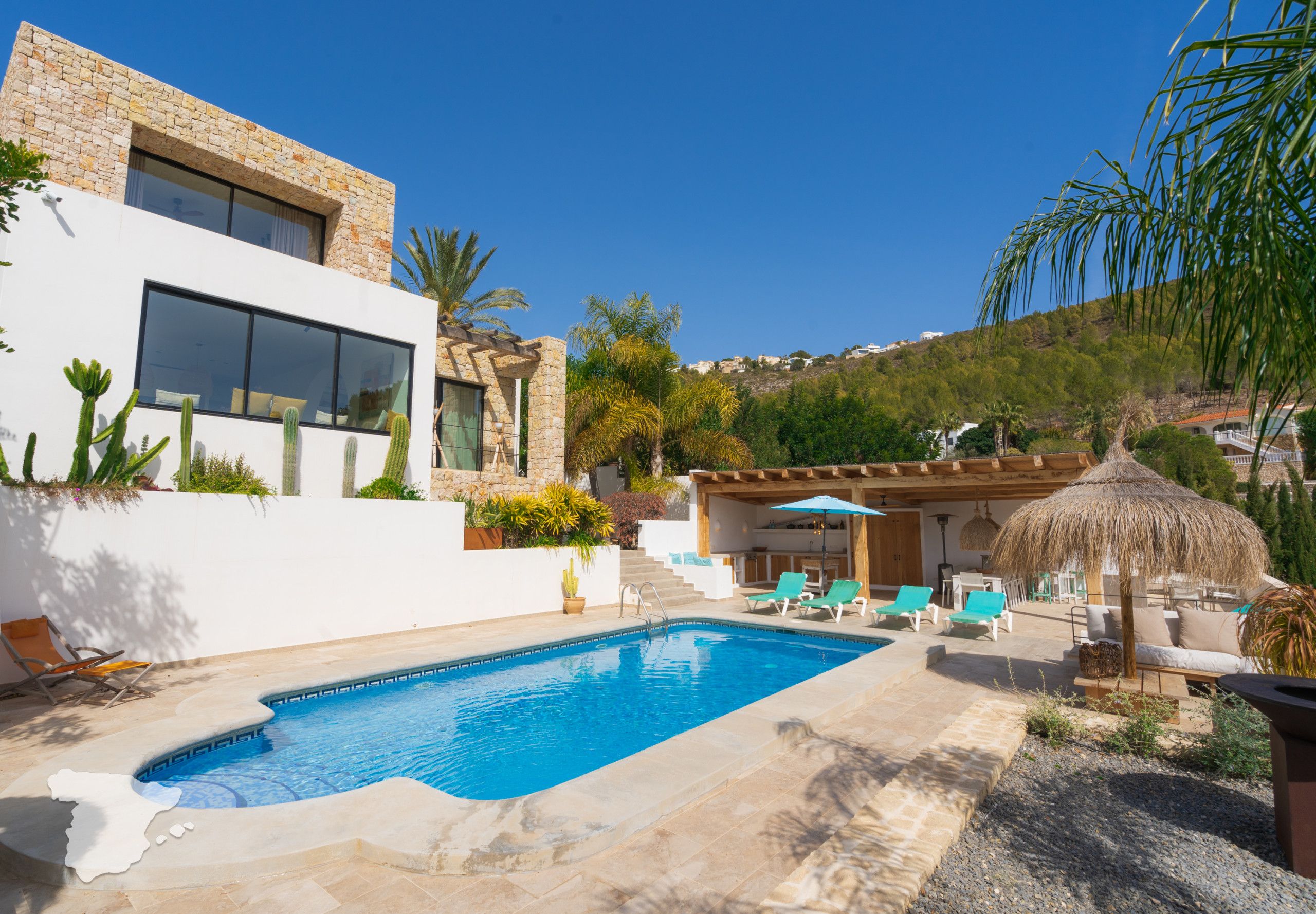A modern house with a swimming pool, outdoor seating, and a view of a hillside.