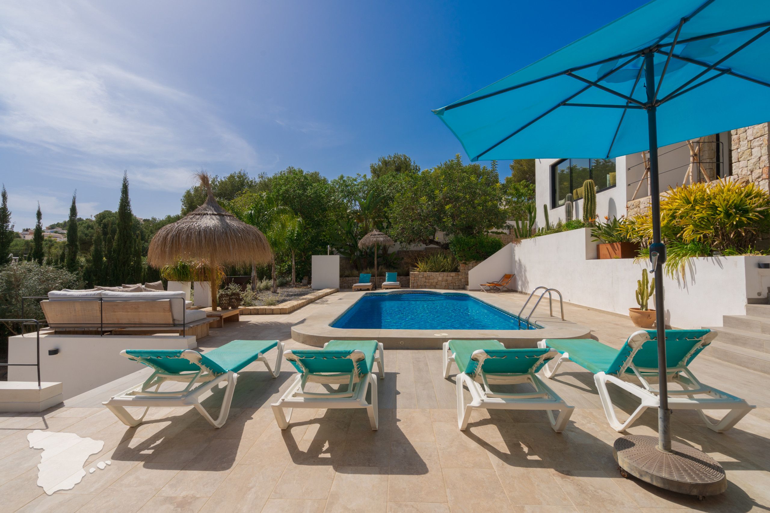 A pool area with lounge chairs and a thatched umbrella.