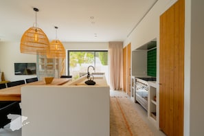 Een moderne keuken met een centraal eiland, houten kasten en een groot raam.