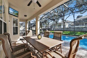 A covered patio with a pool, outdoor furniture, and a television screen. - Royal Retreat - Six Bedroom House, Sleeps 16 (Kissimmee)
