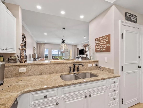 A modern kitchen with granite countertops, white cabinetry, and a stainless steel sink. - Stunning Gulf Views! Steps to beach and heated pools. (Santa Rosa Beach)