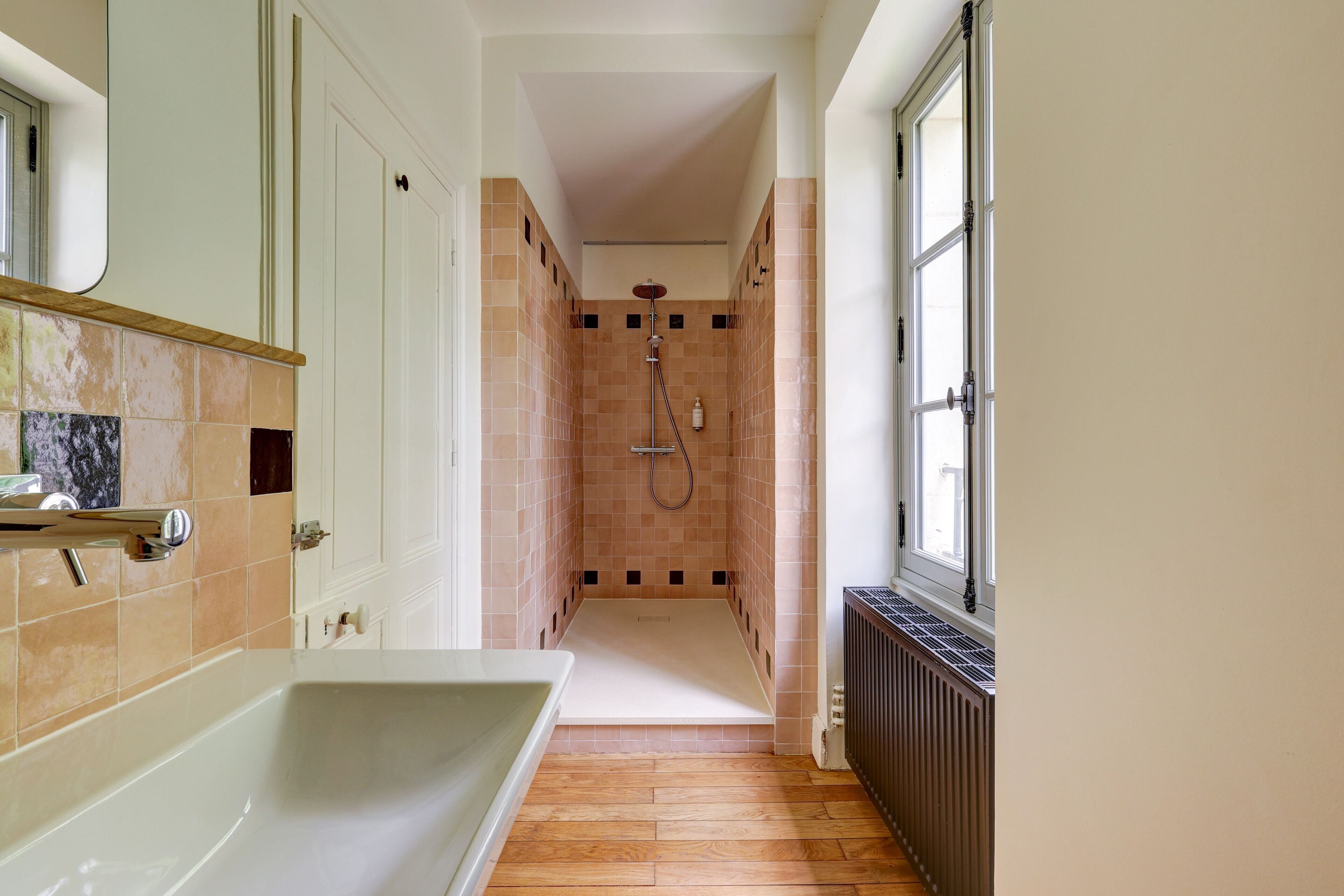 Une petite salle de bain avec une baignoire, une douche et une fenêtre.