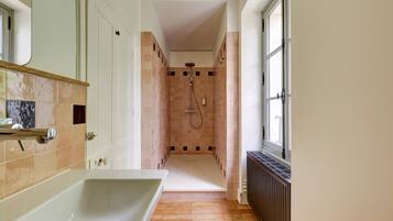 Une petite salle de bain avec une baignoire, une douche et une fenêtre.