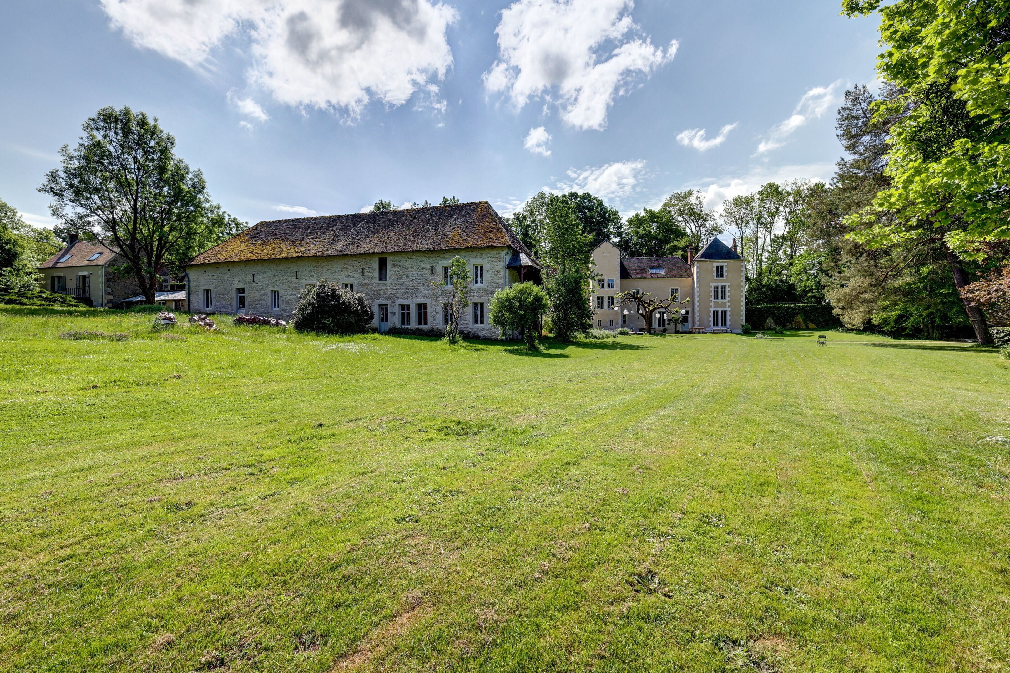 A large stone building with multiple windows and a grassy lawn in front.