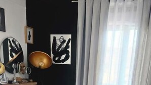 Un dormitorio con cama, cómoda, lámpara y ventana con cortinas.