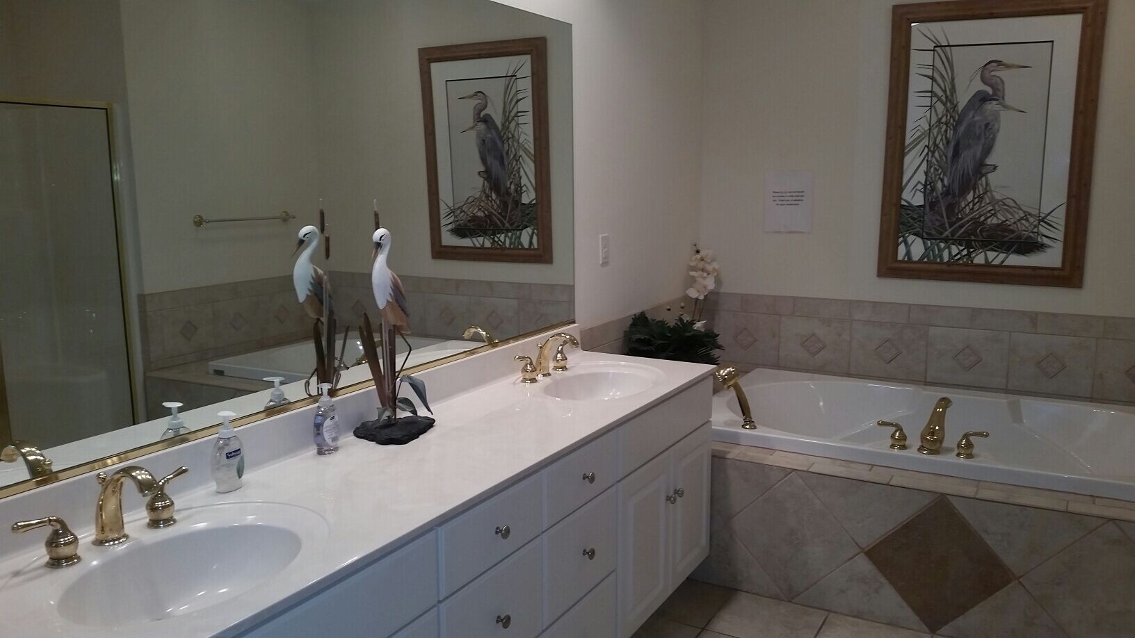 A bathroom with two sinks, a bathtub, and a large mirror.