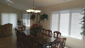 A dining area with a glass-top table, wooden chairs, a chandelier, and potted plants. - 6 Bedroom with an elevator one house back from the beach! (Bethany Beach)