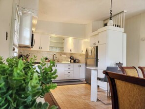 Una cucina moderna con mobili bianchi, un frigorifero in acciaio inossidabile e un'area pranzo con tavolo e sedie.