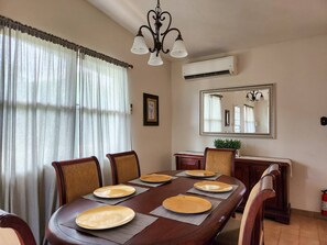Enjoy meals with family and friends at this dining area, featuring a long table and comfortable seating for four.