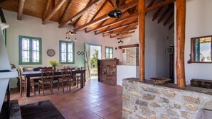 Un interior rústico con chimenea de piedra, vigas de madera y un comedor con mesa y sillas.