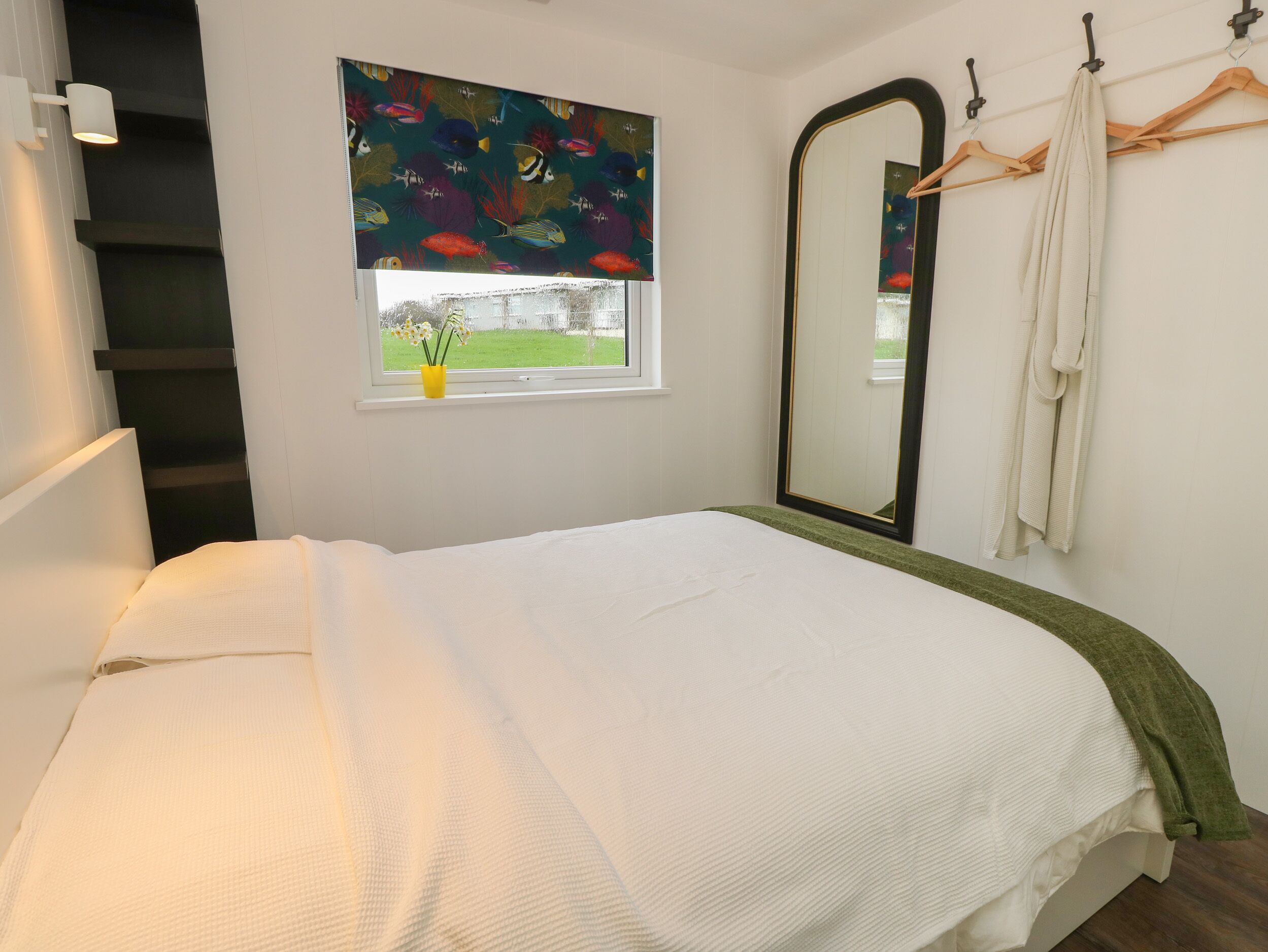 A bedroom with a bed, a window with a view, a mirror, and a towel rack.