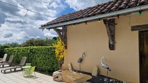 A patio with outdoor furniture, a decorative wall, and a bird bath. - Gîte à la Campagne Avec Piscine (Sarlat-la-Canéda)