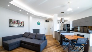 A modern living room with a sectional sofa, a dining table with chairs, and a kitchen area with a central island. - Casa del Marchese del Grillo (Rome)