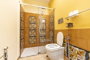 Une salle de bain avec une douche à parois de verre, des toilettes blanches et des carreaux décoratifs sur les murs.
