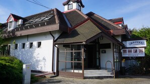 A building with a sloped roof, a small tower, and a signboard. - Május 1 Vendégház - Torony (Torony)