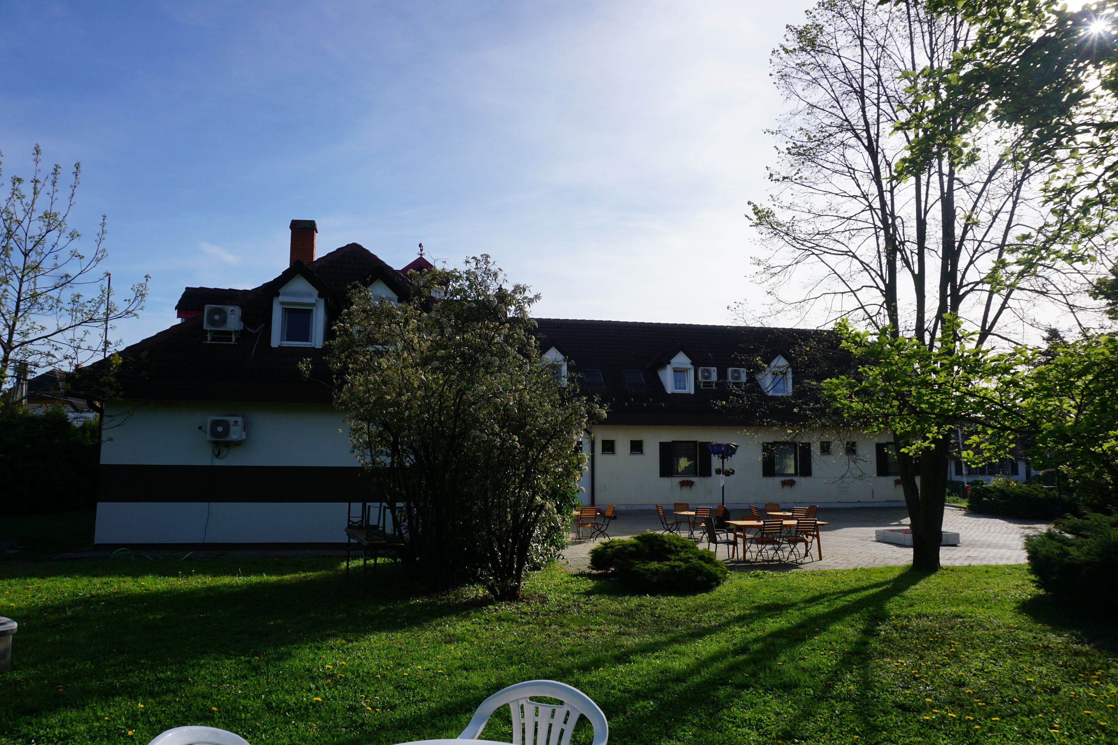 A two-story house with a garden, outdoor seating, and a garage.